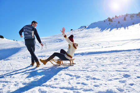 Young Couple Sledding And Enjoying On Sunny Winter Dayの写真素材