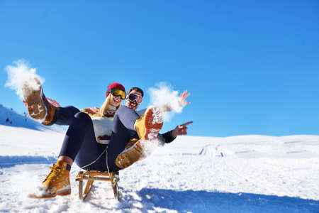 Young Couple Sledding And Enjoying On Sunny Winter Dayの写真素材