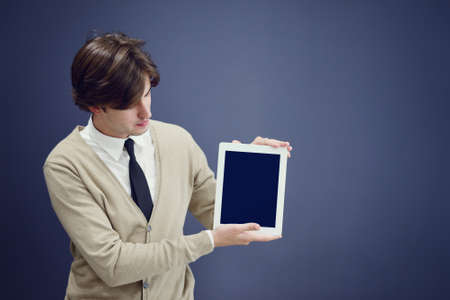 Handsome young man showing something on a tablet, isolated over gray background