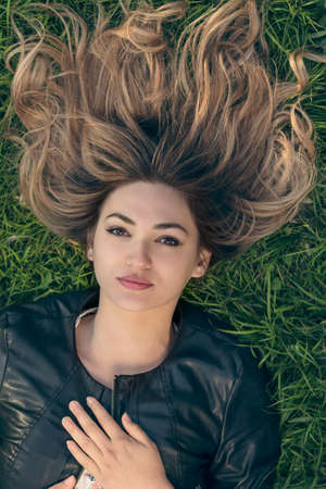 happy young woman laying on the grass in parkの写真素材
