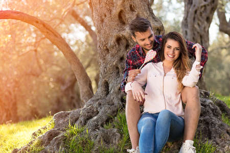 Loving couple under a big tree in the park in autumnの写真素材