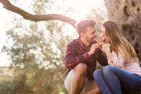 Loving couple under a big tree in the park in autumnの写真素材