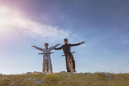 Biker couple with mountain bike pointing in distance at countrysideの写真素材