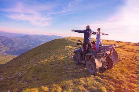 Rear view of young pair near atv. Man is showing something in distance to her girlfriend.の写真素材