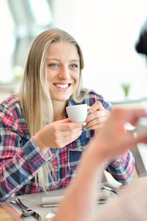 Young couple - man and woman - drinking coffee in a cafe in front of a glass facadeの写真素材