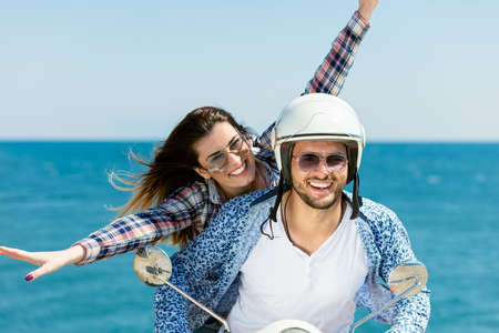 Beautiful young couple in love enjoying and having fun riding on a scooter in a beautiful natureの写真素材