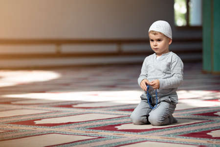 The Muslim child prays in the mosque, the little boy prays to God, Peace and love in the holy month of Ramadan.の写真素材