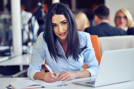 Portrait of pretty businesswoman working in the office and looks busy while making a note on the notebookの写真素材