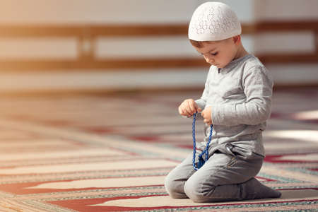 The Muslim child prays in the mosque, the little boy prays to God, Peace and love in the holy month of Ramadan.の写真素材