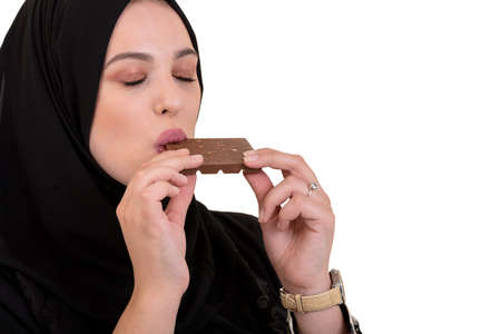 Lovely smiling muslim woman with hijab eating chocolate isolated on white background.の写真素材