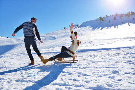 Young Couple Sledding And Enjoying On Sunny Winter Day
