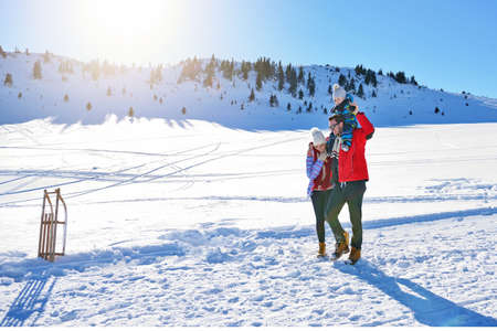 happy young family playing in fresh snow at beautiful sunny winter day outdoor in natureの写真素材