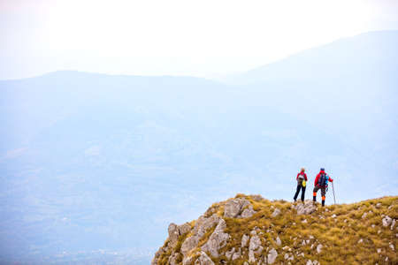 adventure, travel, tourism, hike and people concept - smiling couple walking with backpacks outdoorsの写真素材