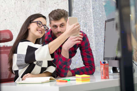 Business people making photos on mobile or smart phone and happy smiling. Workers having break time. Business concept.の写真素材