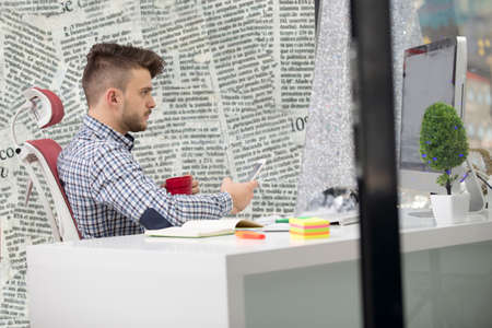 Young happy businessman smiling while reading his smartphone.の写真素材