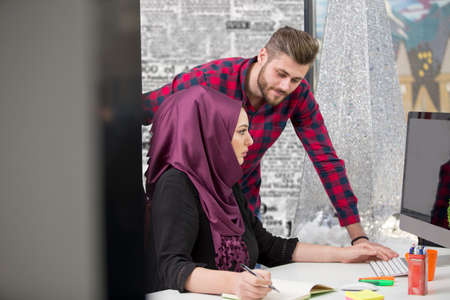 international multicultural team at work: asian muslim woman and caucasian man.の写真素材