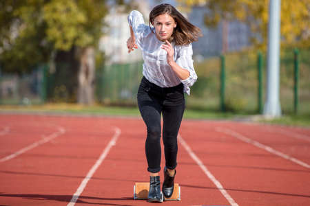business woman in start position ready to run and sprint on athletics racing trackの写真素材