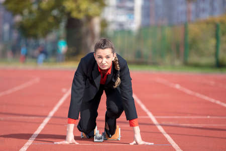 business woman in start position ready to run and sprint on athletics racing trackの写真素材