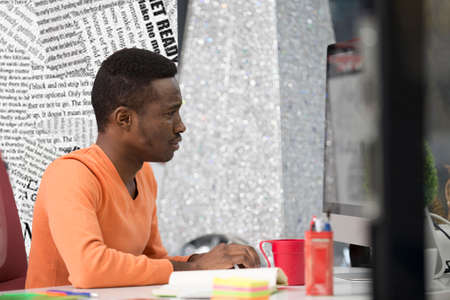 Young Black Man in the office behind his deskの写真素材