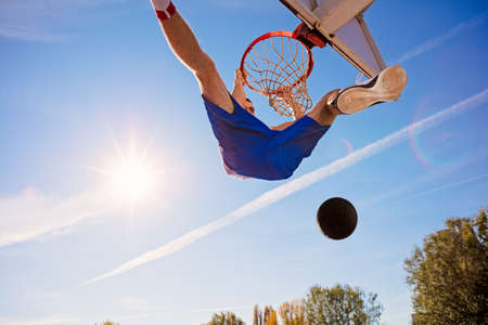 Slam Dunk. Side view of young basketball player making slam dunkの写真素材