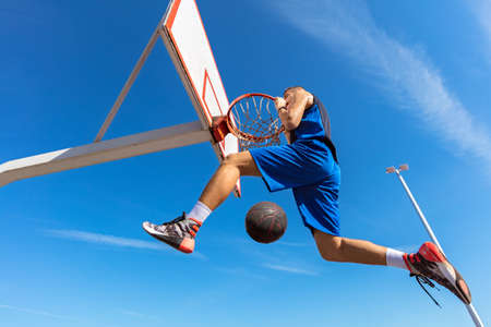 Slam Dunk. Side view of young basketball player making slam dunk