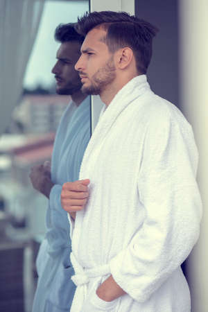Morning portrait of handsome young man in bathrobeの写真素材