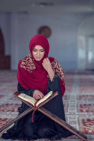 Muslim Woman Reading Koran Or Quran Wearing Traditional Dress At The Mosqueの写真素材