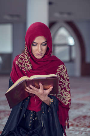 Muslim Woman Reading Koran Or Quran Wearing Traditional Dress At The Mosqueの写真素材