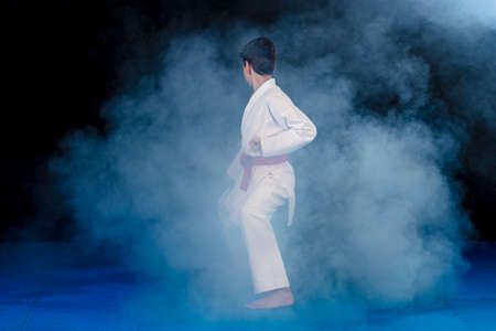 Pre-teen boy doing karate on a black background with smokeの写真素材