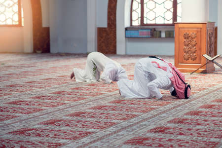 Muslim man and woman praying for Allah in the mosque togetherの写真素材