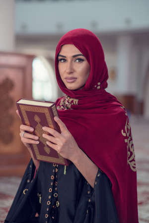 Muslim Woman Reading Koran Or Quran Wearing Traditional Dress At The Mosque