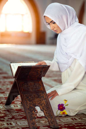Young muslim woman praying in mosque with quranの写真素材