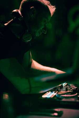 Club, disco DJ playing and mixing music for crowd of happy people. Nightlife, concert lights,...