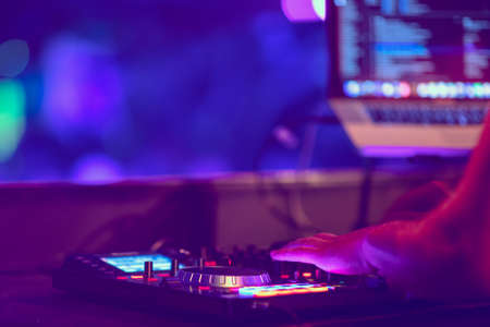 Dj mixes the track in the nightclub at party. DJ hands in motion