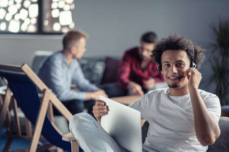 Laughing african american hipster software developer at computer at office of startup company