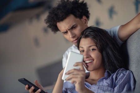 Young attractive diverse couple browsing internet, using laptop computer, smiling.