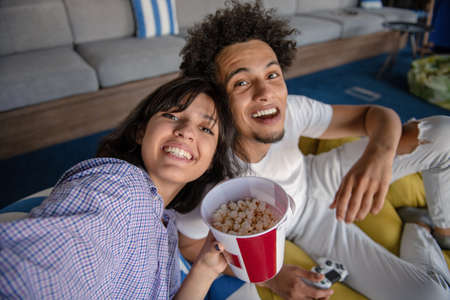 Playful young couple playing video games in their living room.の写真素材