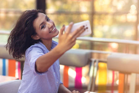 Young woman taking a selfie in coffee shopの写真素材
