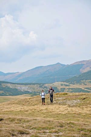 Sporty hikers on path with trekking poles