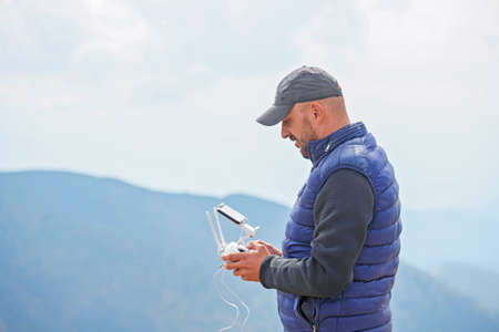 Bearded male model use drone remote control to fly device in air. Man operating drone flying in...