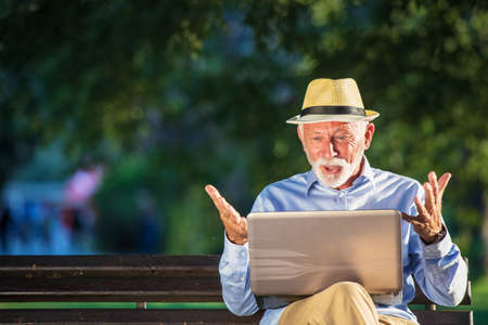 Senior man using laptop computer at rest in the park outdoors