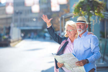 Senior couple of tourists looking at city mapの写真素材