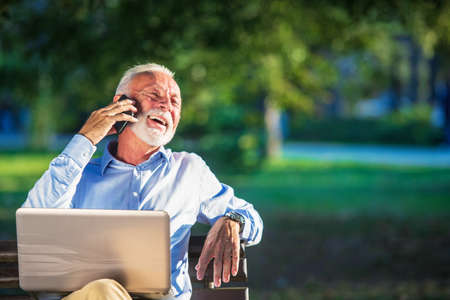 Business correspondence. Focused mature businessman using laptop while sitting in park