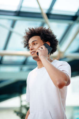 Young man looking away while talking on mobile phone in cafe