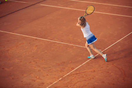 Woman playing tennis on clay court, with sporty outfit and healthy lifestyleの写真素材