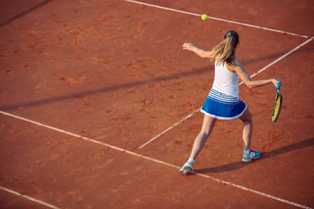 Young woman playing tennis on clay. Forehand.の写真素材