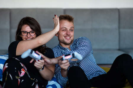 Young smiling couple playing videogames at home.