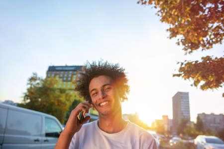 happy smiling urban hipster young man using smart phone. African american teenager holding mobile...