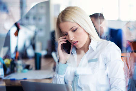 business concept - businesswoman talking on the phone in officeの写真素材