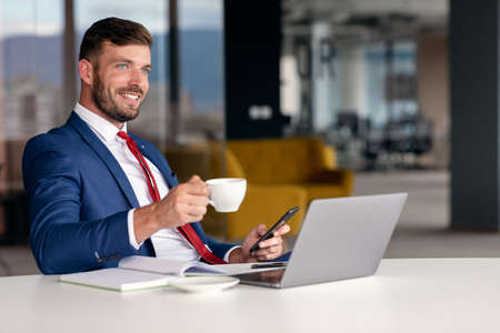 Portrait of young man sitting at his desk in the officeの写真素材